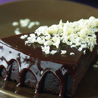 a piece of chocolate cake sitting on top of a brown plate with white sprinkles