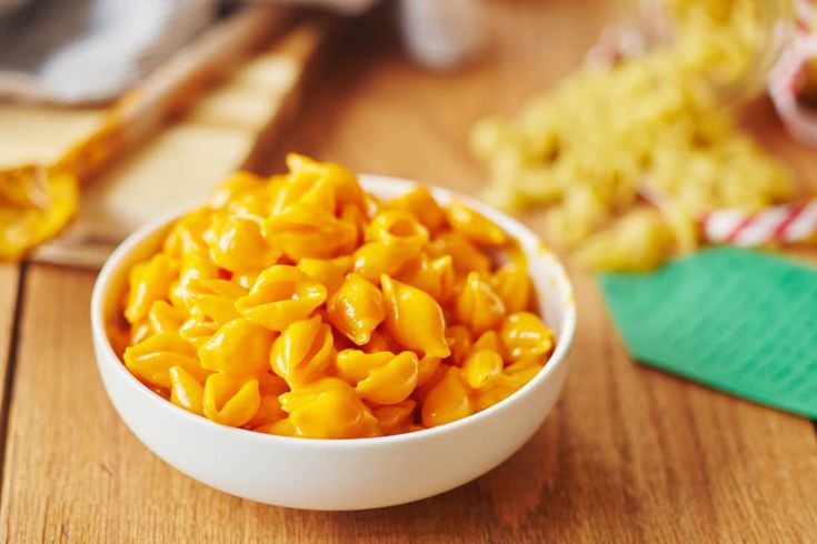 a white bowl filled with macaroni and cheese on top of a wooden table