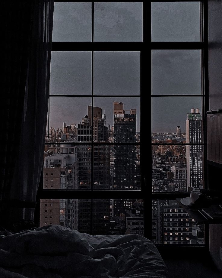 a bedroom with a view of the city from it's window sill at night