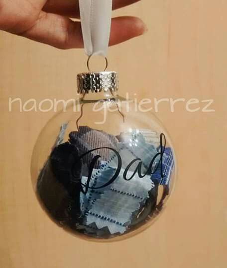 a hand holding a glass ornament with the word dad written in black ink