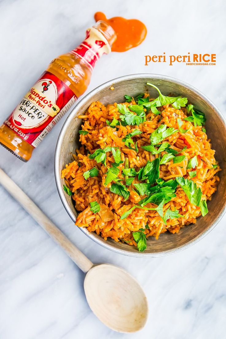 a bowl filled with rice and vegetables next to a bottle of ketchup on the side