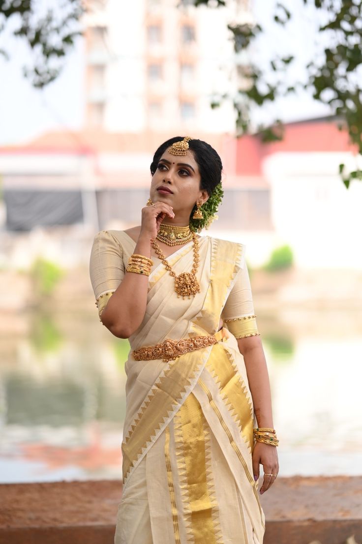 a woman in a yellow and white sari is talking on her cell phone while standing by the water