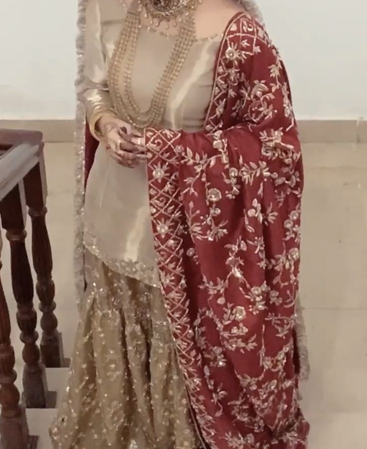 a woman in a red and gold outfit standing on a stair case next to a railing