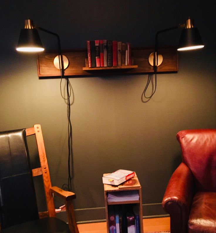 a chair and table in a room with two lamps on the wall next to each other