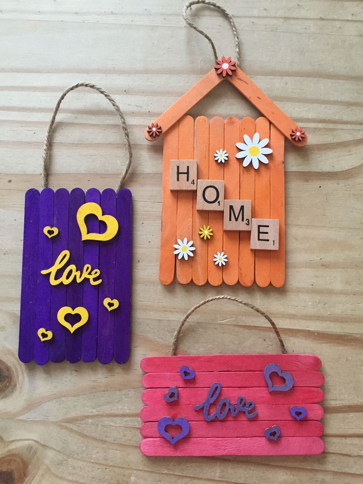 three popsicle crafts are hanging on a wooden table with the words home and love spelled across them