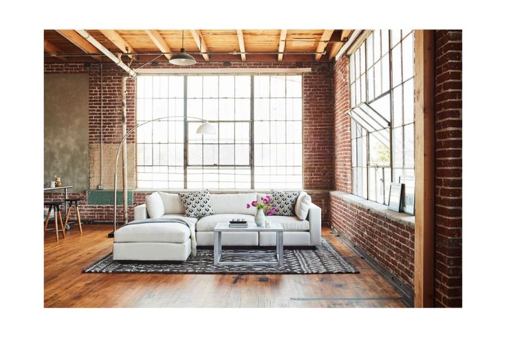 a living room with brick walls and wooden floors is pictured in this image, there are two couches facing each other