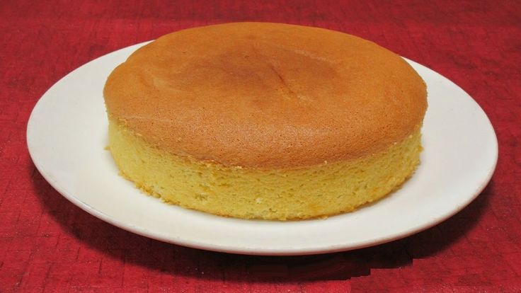 a yellow cake on a white plate sitting on a red table