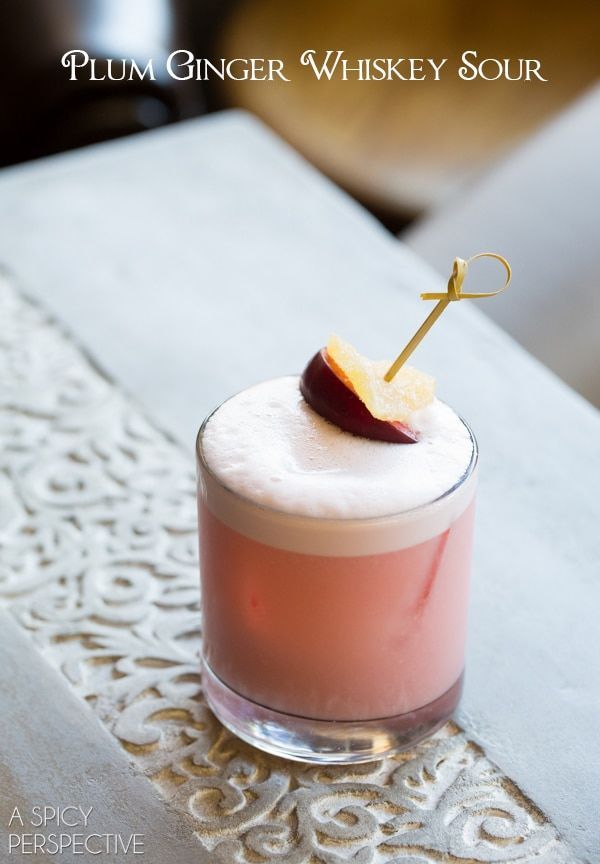 a pink cocktail with an apple on the top and a gold stick sticking out of it