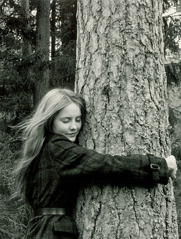 a woman leaning against a tree in the woods