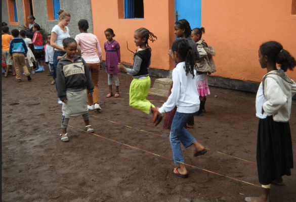 a group of young children standing next to each other in front of a yellow building