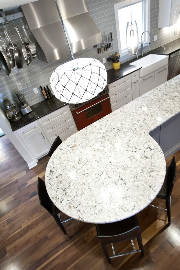 a large kitchen with an island and stainless steel appliances in the center, surrounded by white cabinets