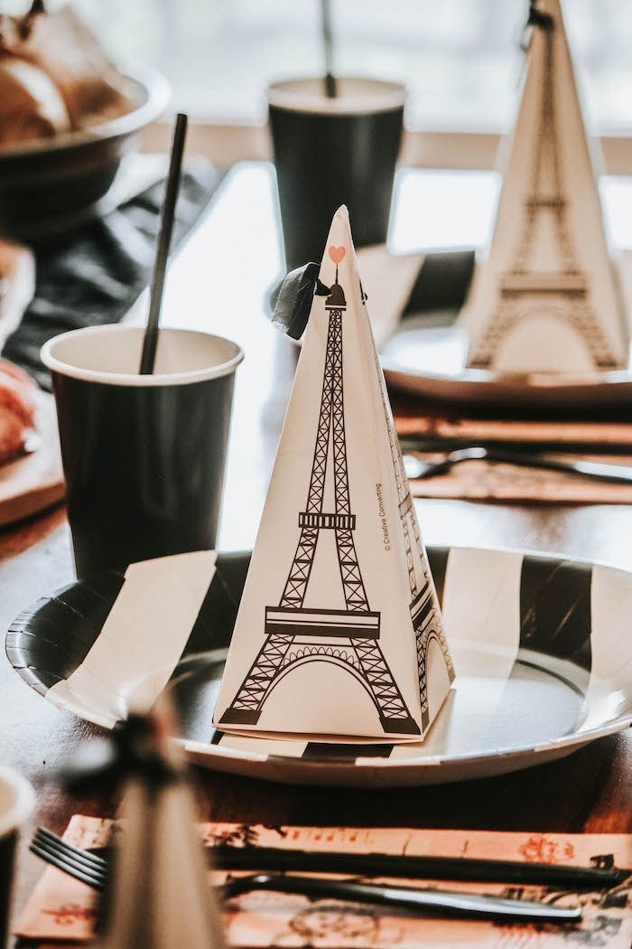 a table with plates, cups and napkins that have the eiffel tower on them