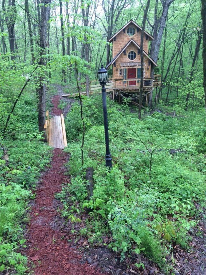 a small cabin in the woods with a path leading to it and a lamp post