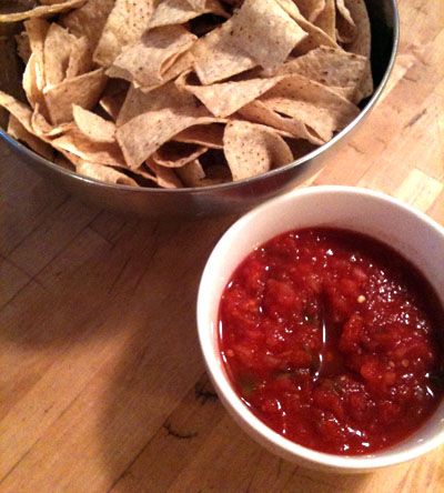 a bowl of salsa and chips on a wooden table