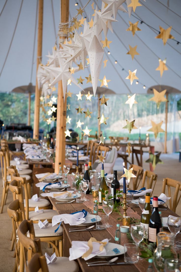 a long table is set with paper stars hanging from the ceiling and place settings for dinner