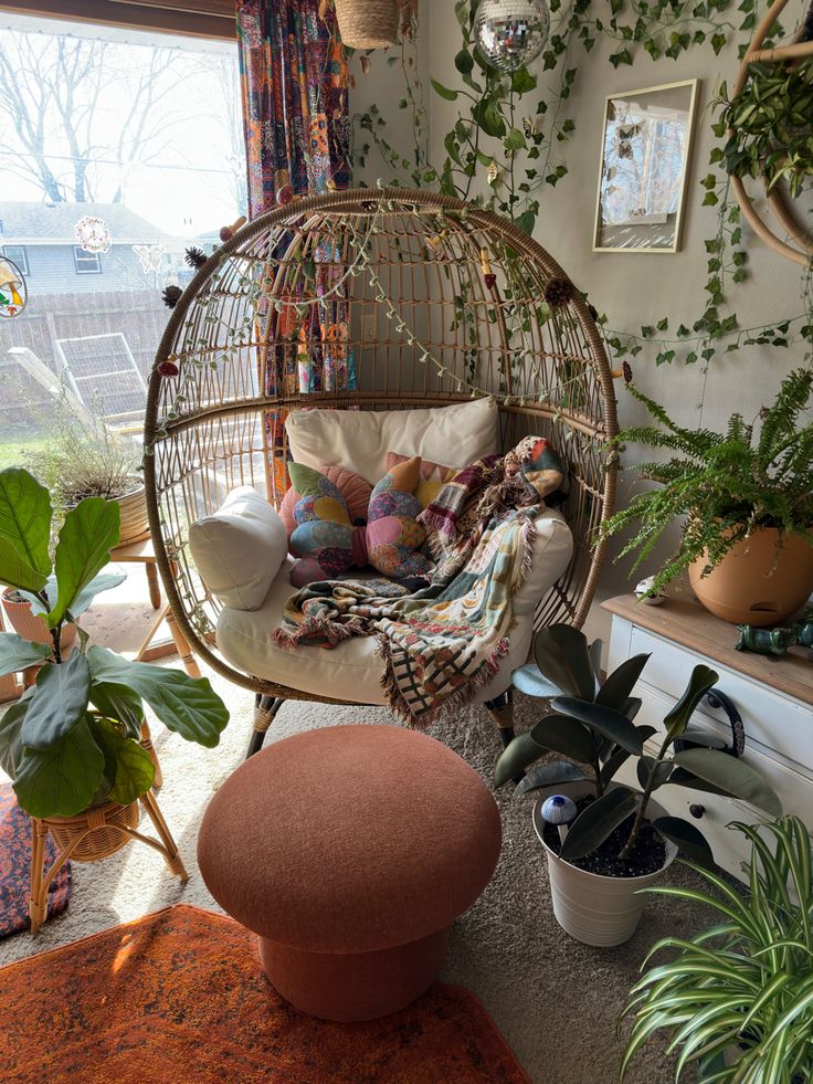 a living room filled with lots of plants next to a window and a hanging chair