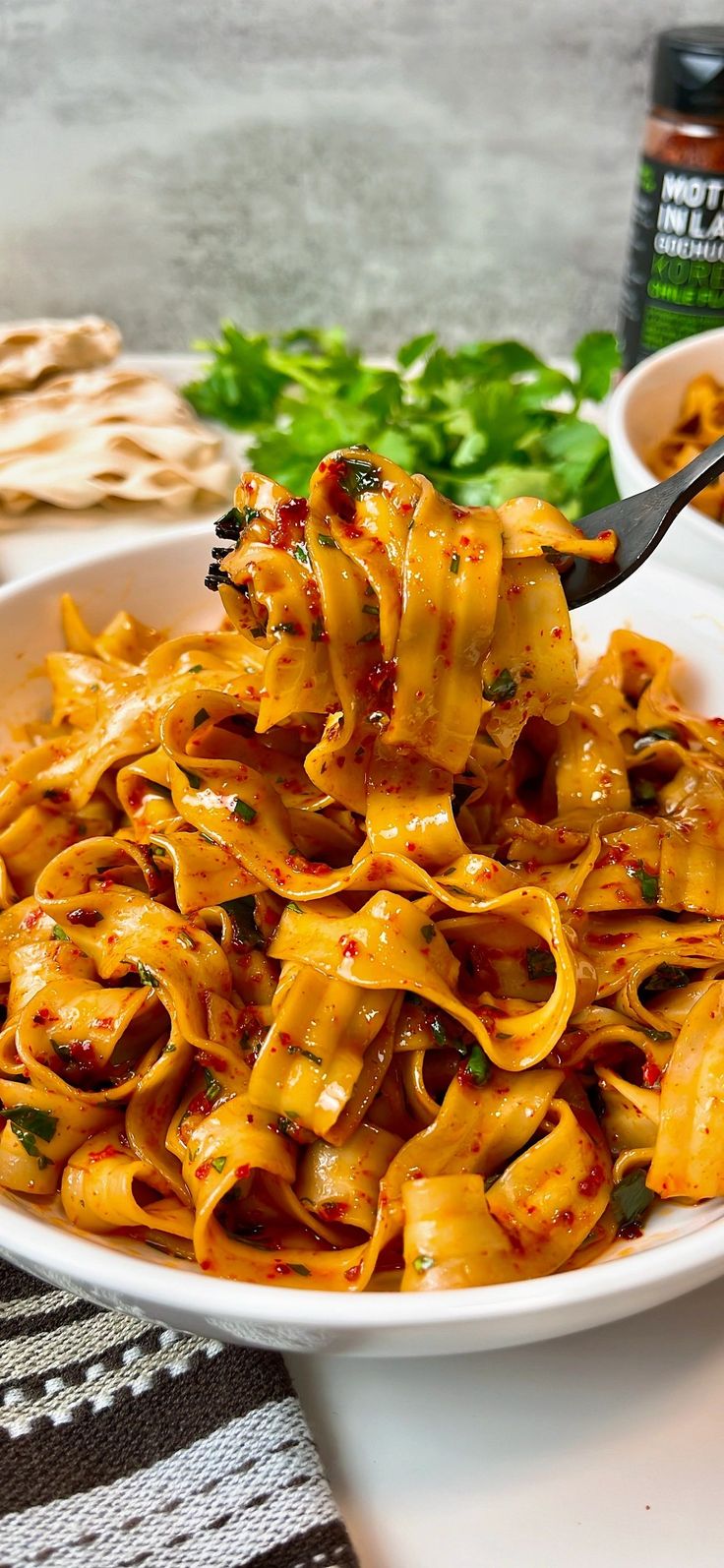 a white bowl filled with pasta and sauce on top of a table next to crackers