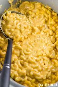 a bowl filled with macaroni and cheese on top of a table next to a spoon