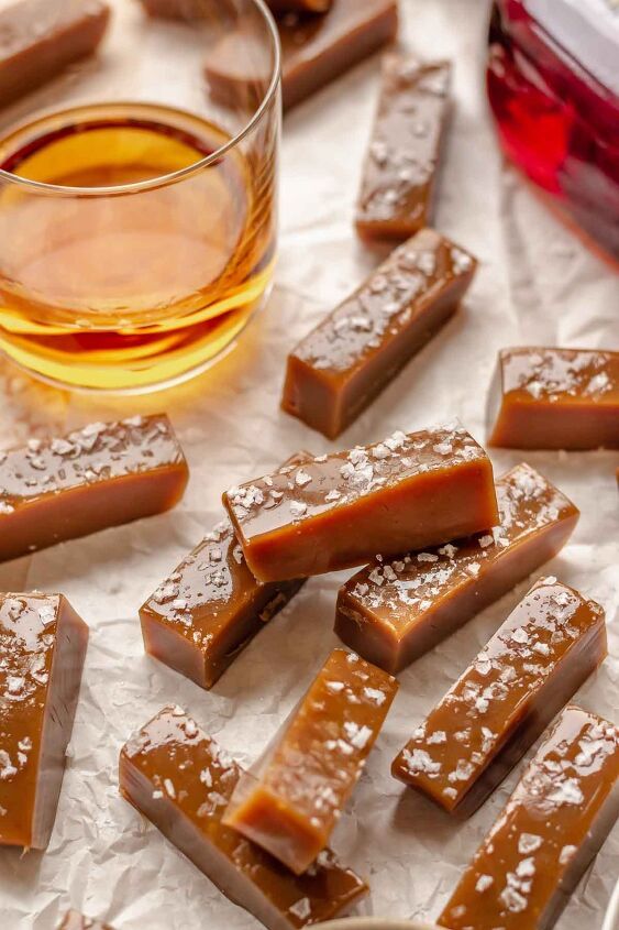 several pieces of fudge sit on wax paper next to a glass of liquid and spoon