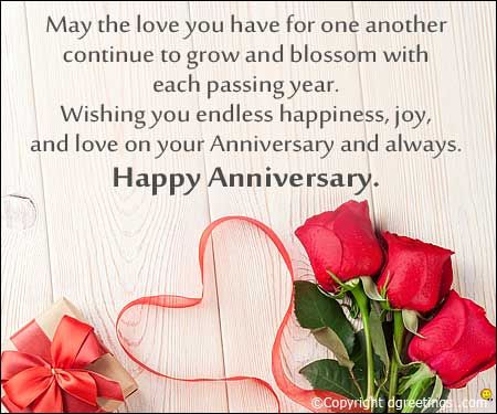 two roses and a heart on a white wooden background with the words happy anniversary written below