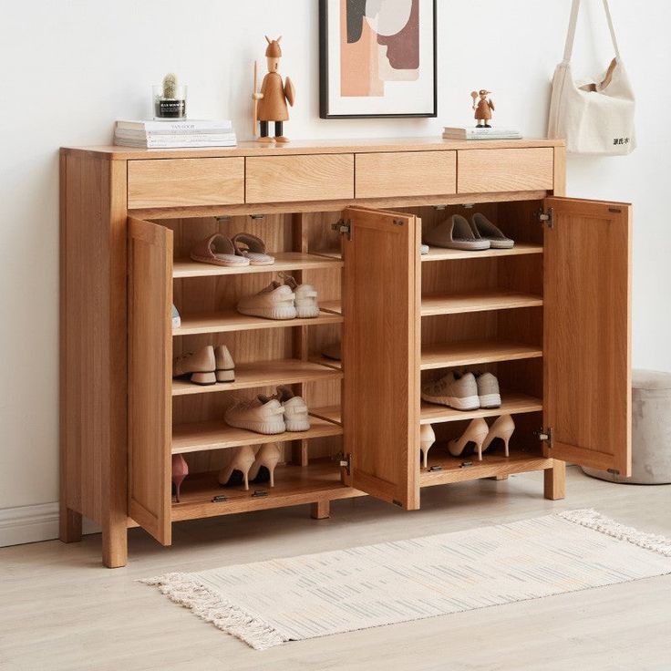 a wooden cabinet with shoes on it in front of a white wall and carpeted floor