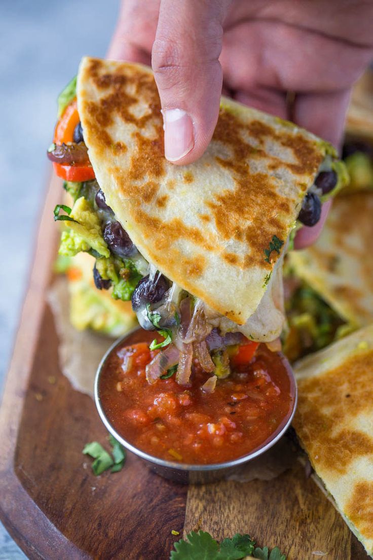 a person is dipping salsa into a tortilla