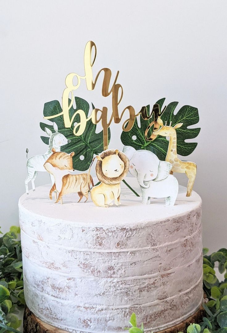 a white cake topped with animals and greenery