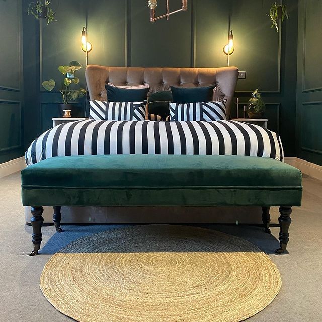 a bedroom with green walls, striped bedding and an upholstered headboard