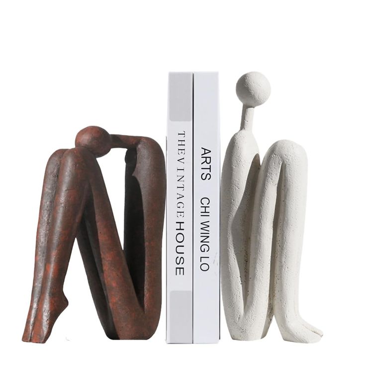 two figurines sitting next to each other in front of a bookend and box