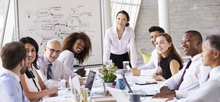 a group of business people sitting around a conference table with a whiteboard in the background