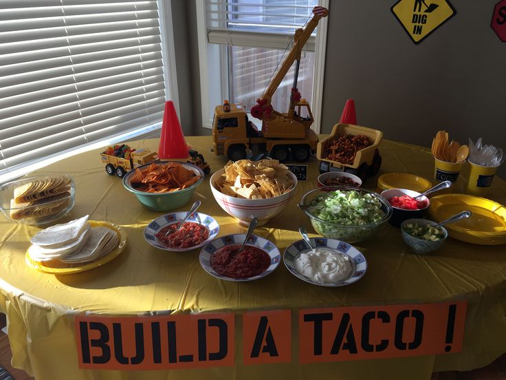 a table topped with bowls filled with food next to construction cones and traffic cones on top of a yellow table cloth