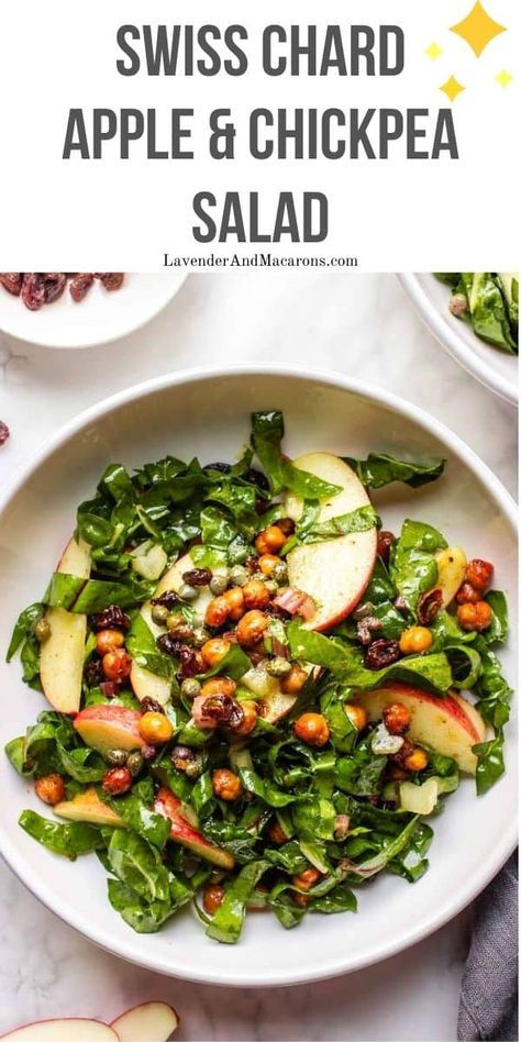 a white bowl filled with spinach, apples and chickpea salad on top of a table