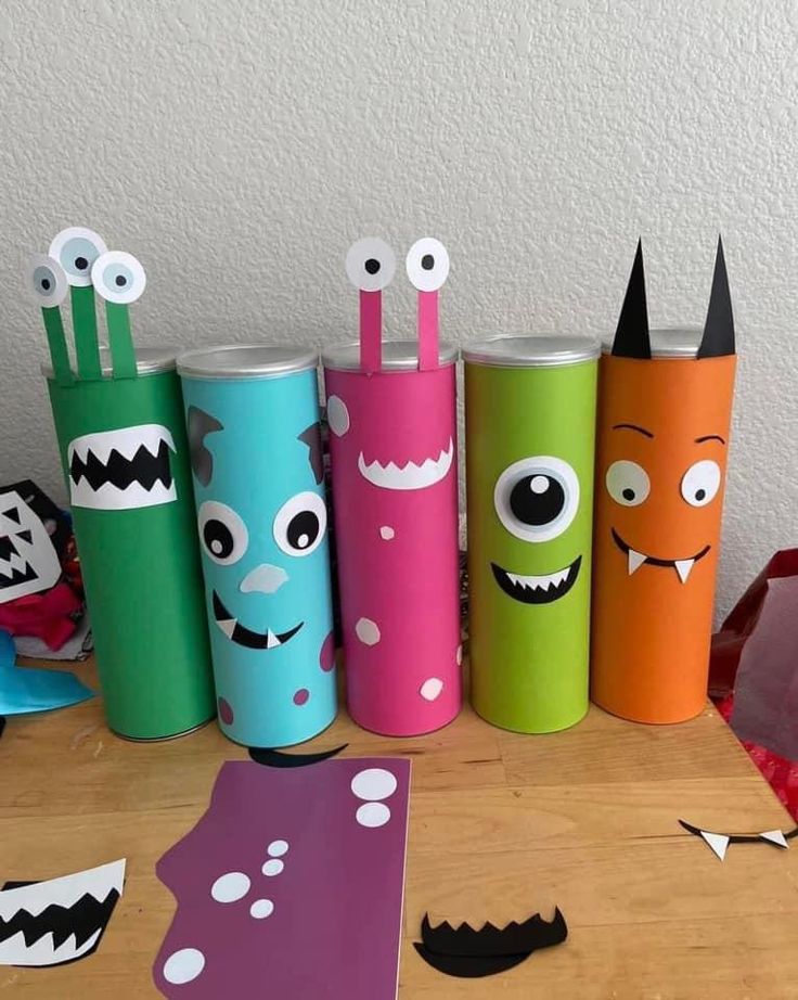 several different colored paper tubes with faces and eyes on them sitting on a wooden table