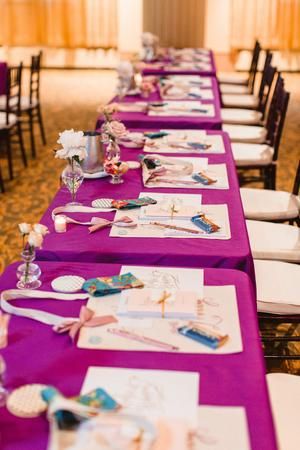 a long table is set up with purple linens and place settings for the guests