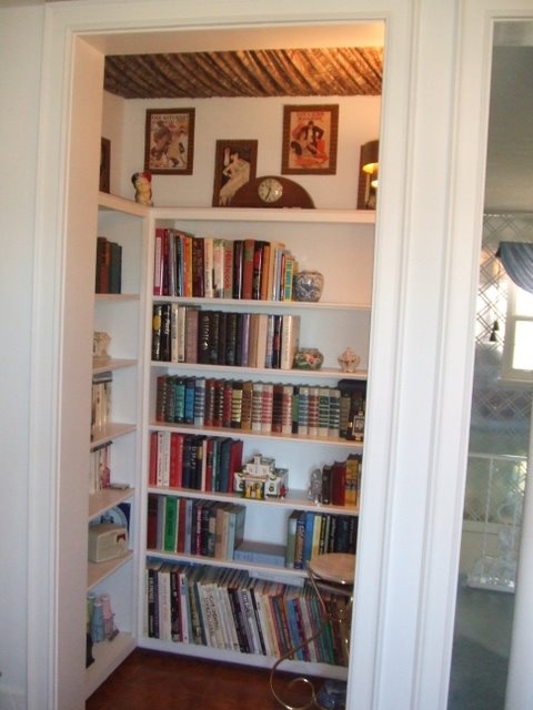 a white book shelf filled with lots of books next to a doorway leading into another room