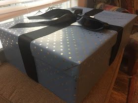 a blue gift box sitting on top of a couch next to a window with polka dots