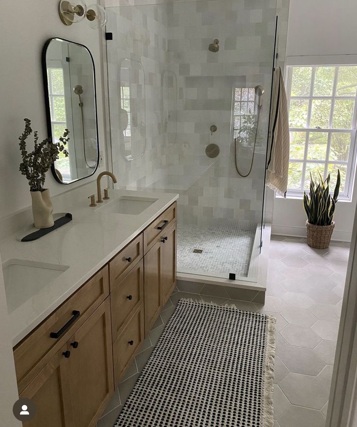 a bathroom with two sinks, a shower and a large mirror on the wall above it