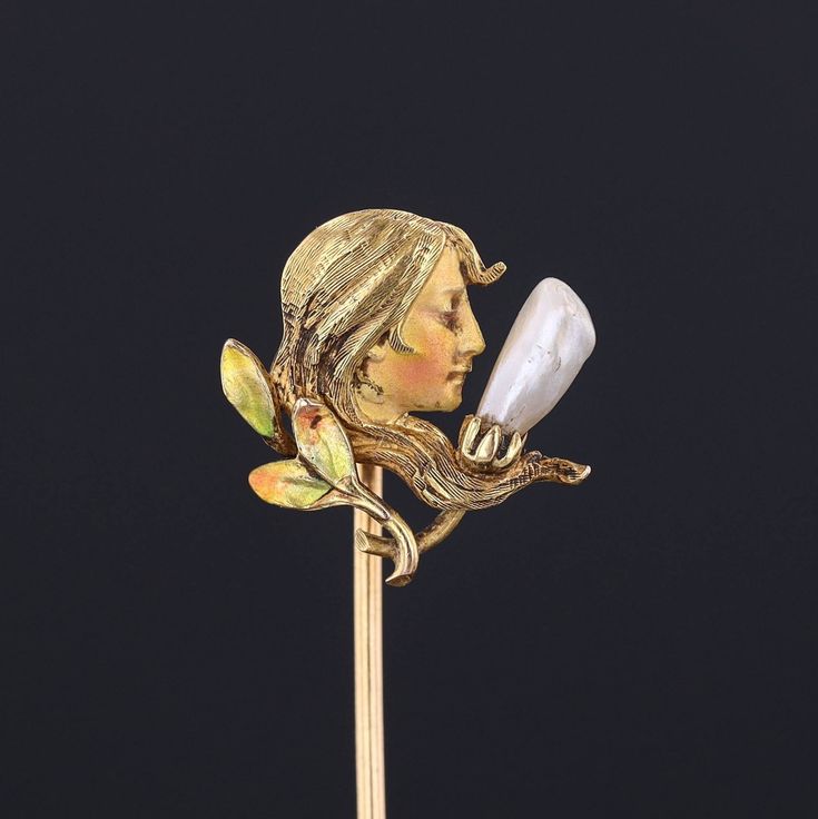 During the turn of the nineteenth century, artisans working in the Art Nouveau style were inspired by the changing roles of women in society and began depicting the free flowing feminine form in brooches, bracelets, rings and more. This antique stick pin (circa 1910-1920) features a woman of 14k gold decked out in enamel and accented with a single pearl. The piece bears the makers mark for the renowned Krementz and Co. The pin head measures 0.6 inches by 0.6 inches and 2.4 inches long. The piece Women In Society, Vintage Baptism, Pin Head, Antique Pins, Single Pearl, Pearl Pin, Jewelry Post, Pin Art, Art Nouveau Style