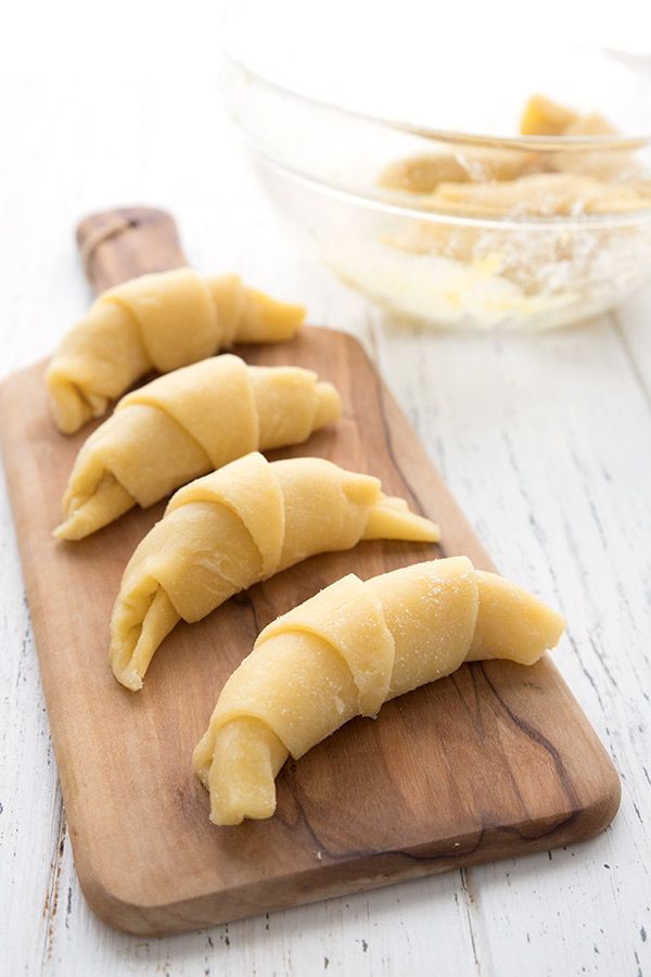 four uncooked dumplings on a wooden cutting board