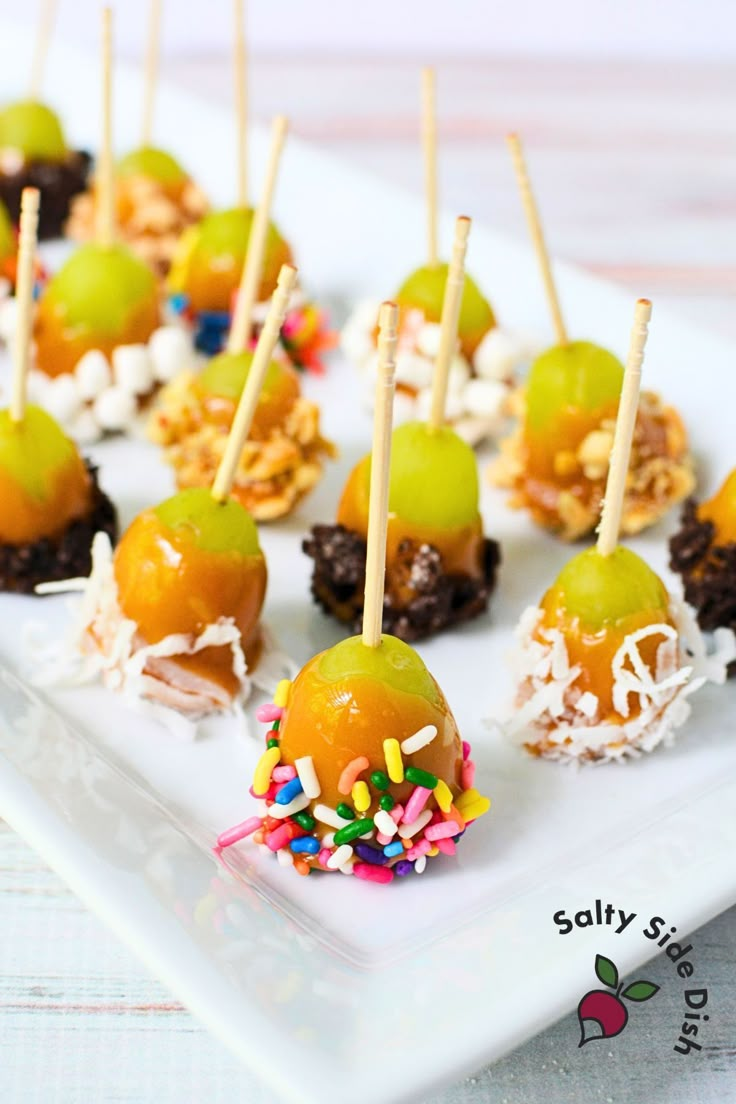 small desserts are arranged on a white plate with toothpicks and sprinkles