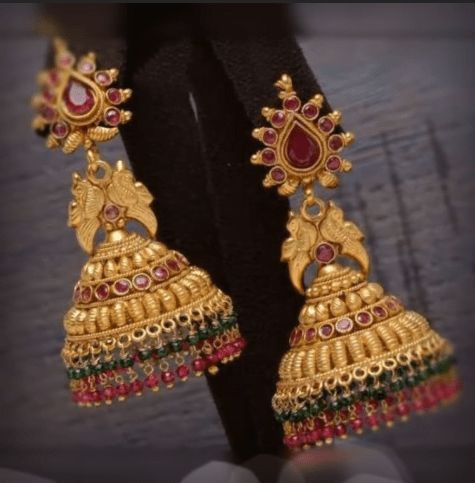 gold plated earrings with red and green stones on the bottom, hanging from a black piece