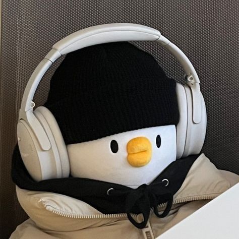 a stuffed penguin wearing headphones sitting on top of a white table next to a wall