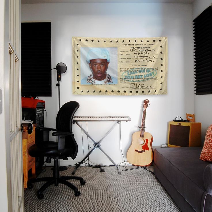 a room with a couch, guitar and music equipment on the wall next to it