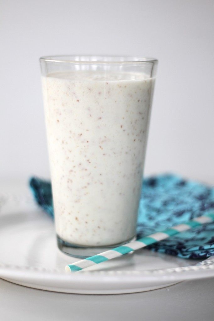 a glass filled with milk sitting on top of a blue and white place mat next to a spoon