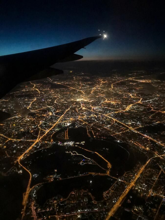 an airplane wing flying over a city at night