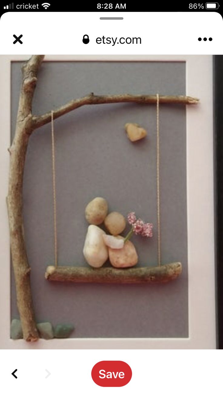 a photo frame with some rocks on it and a tree branch hanging from the side