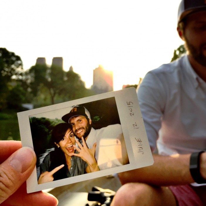 a man holding up a polaroid with a woman on it