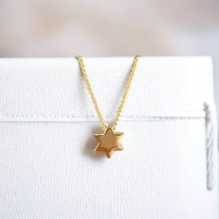 Elegant Star of David Necklace: Timeless symbol of faith, crafted with precision. Pictured at 16" and 18" adjustable lengths. Sterling Silver 14K Gold Plate 16" + 2" 10mm diameter Sugar Bean Jewelry's complimentary packaging adds an extra special touch to your jewelry purchase. Our dainty glass bottle and pouch will showcase your piece with style and sophistication. Yellow Gold Star Of David Charm Necklace Gift, Yellow Gold Star Of David Charm Necklace, Silver Star Of David Necklace In 14k Gold, 14k Gold Silver Star Of David Necklace, Dainty Yellow Gold Star Of David Necklace, Yellow Gold Charm Necklace With Star Of David Charm, Gift White Gold Necklace With Star Charm, White Gold Necklace With Star Charm As Gift, Spiritual Yellow Gold Necklace With Star Charm