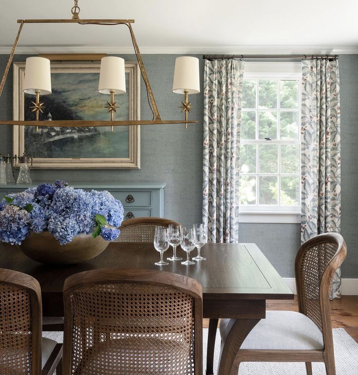 a dining room table with chairs and a vase of blue flowers on the centerpiece