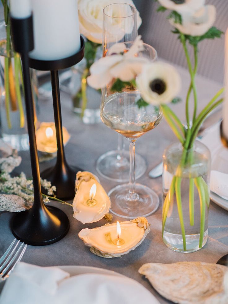 the table is set with candles, flowers and seashells for an elegant dinner